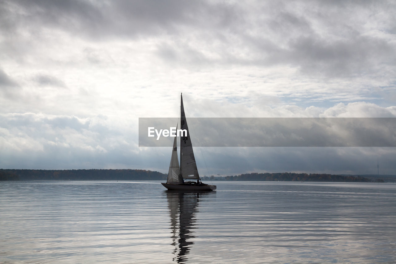 Sailboat sailing in lake against sky