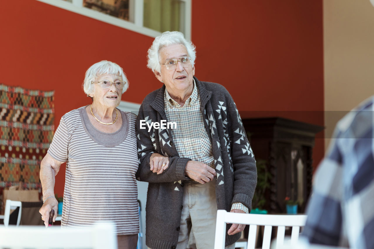 Senior couple standing arm in arm at nursing home