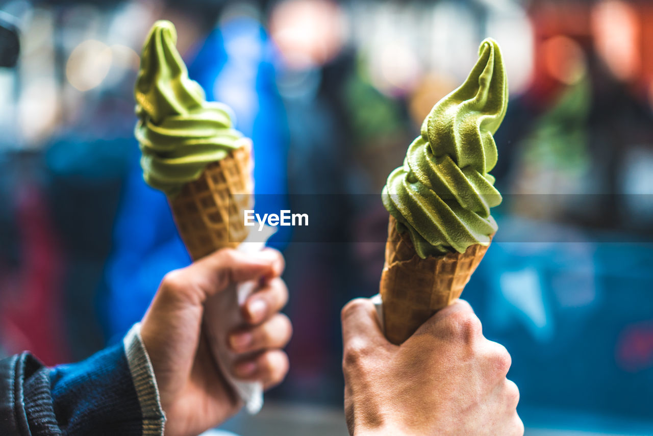 Cropped hands of people holding ice creams outdoors