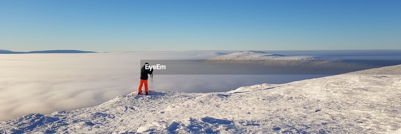 Panoramic view of person on snowcapped mountain against sky