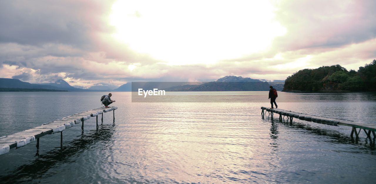 MAN IN SEA AGAINST SKY DURING SUNSET