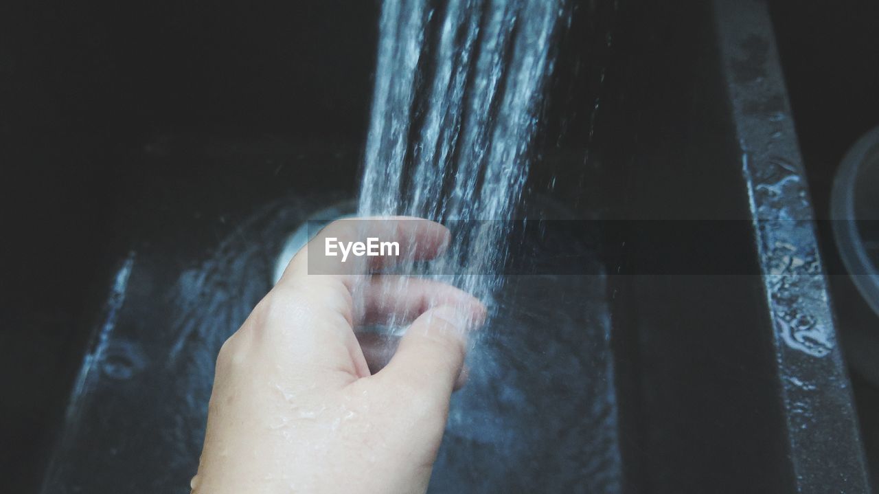 Cropped image of person washing hand in sink
