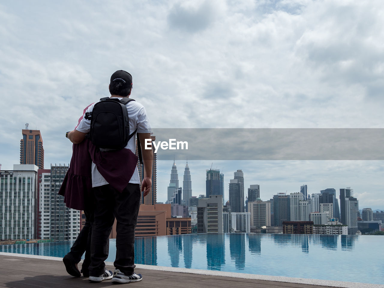 Rear view of couple standing by cityscape against sky