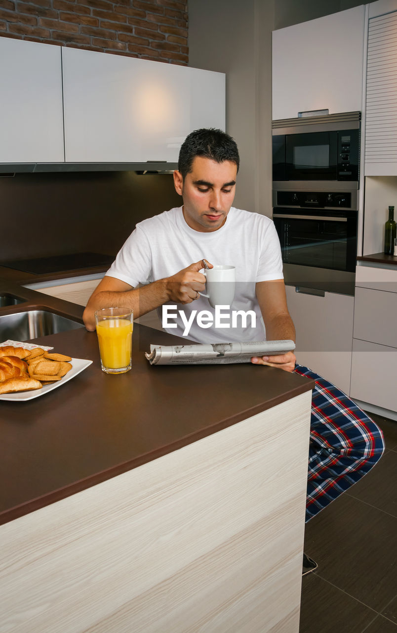 Man holding coffee cup in kitchen