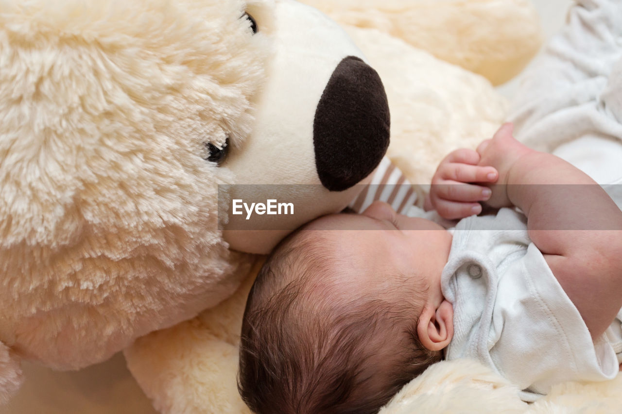 CLOSE-UP OF BABY SLEEPING WITH TOY ON BED