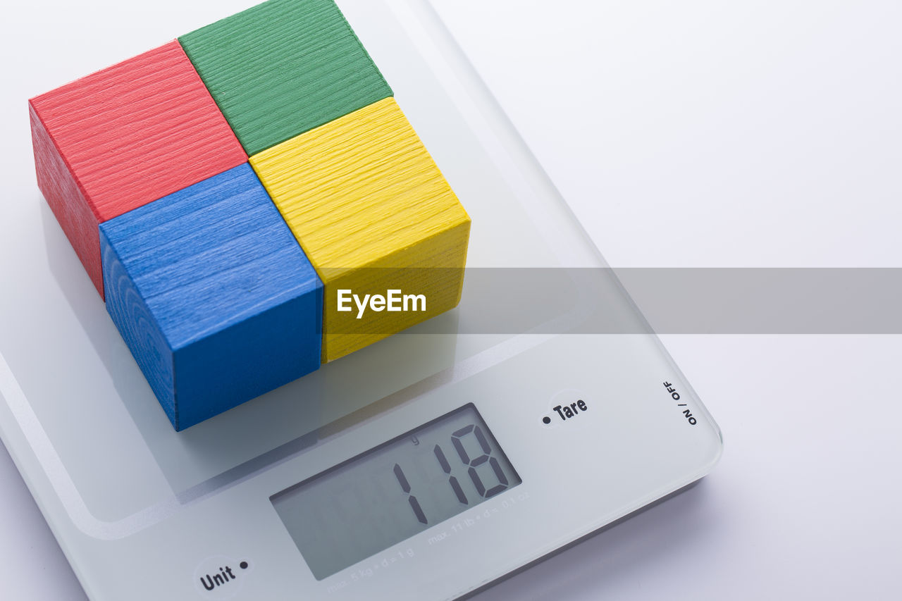 Colorful wooden blocks on weight scale over white background