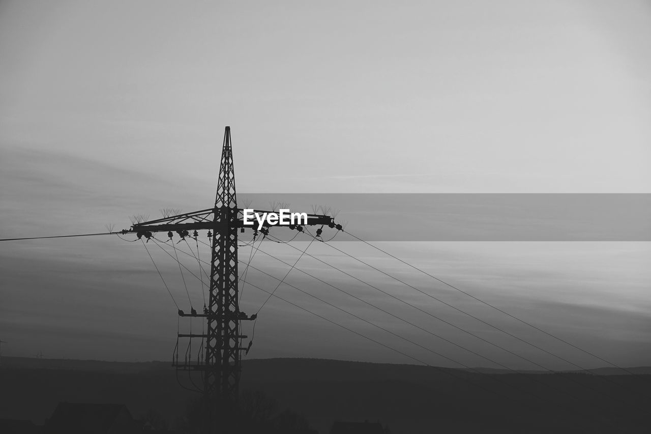 Low angle view of silhouette electricity pylon against sky