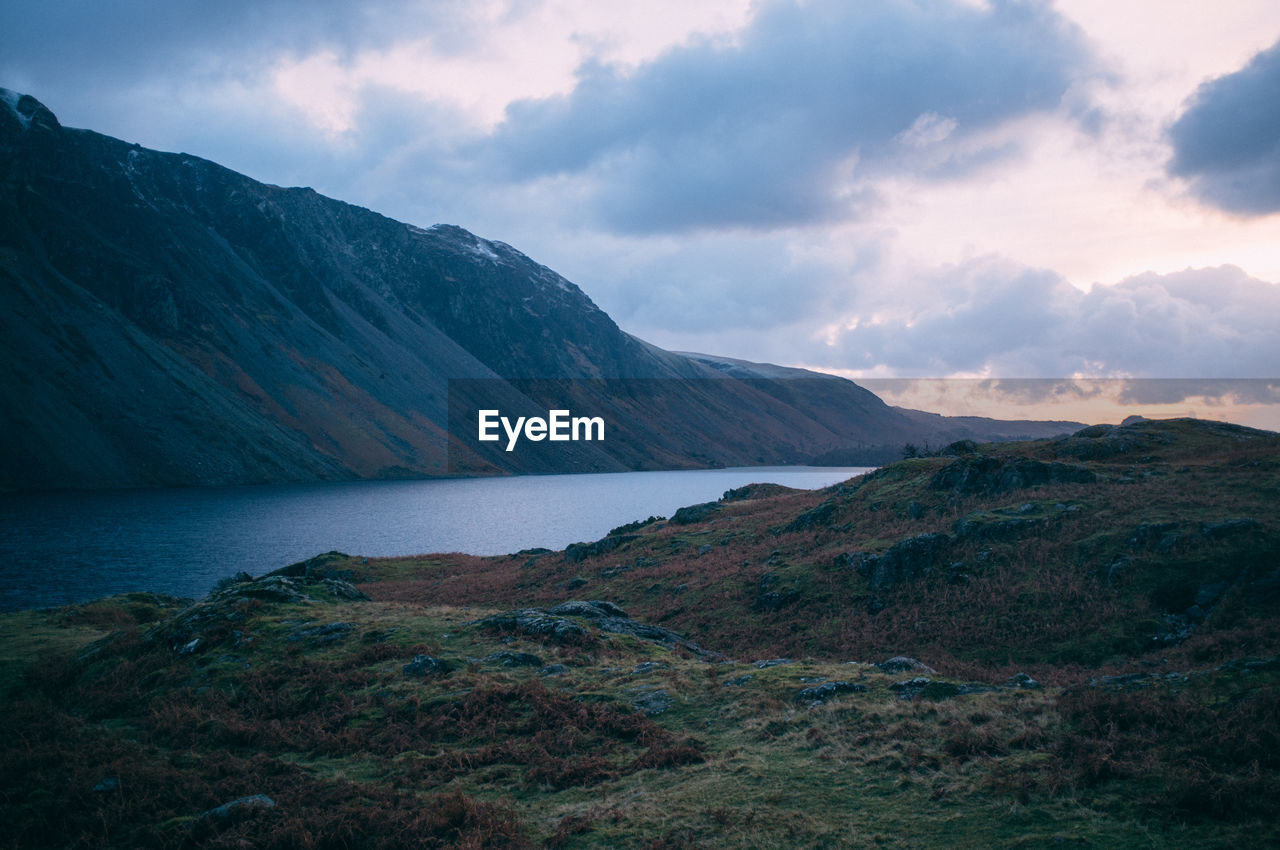 Scenic view of mountains and lake against cloudy sky