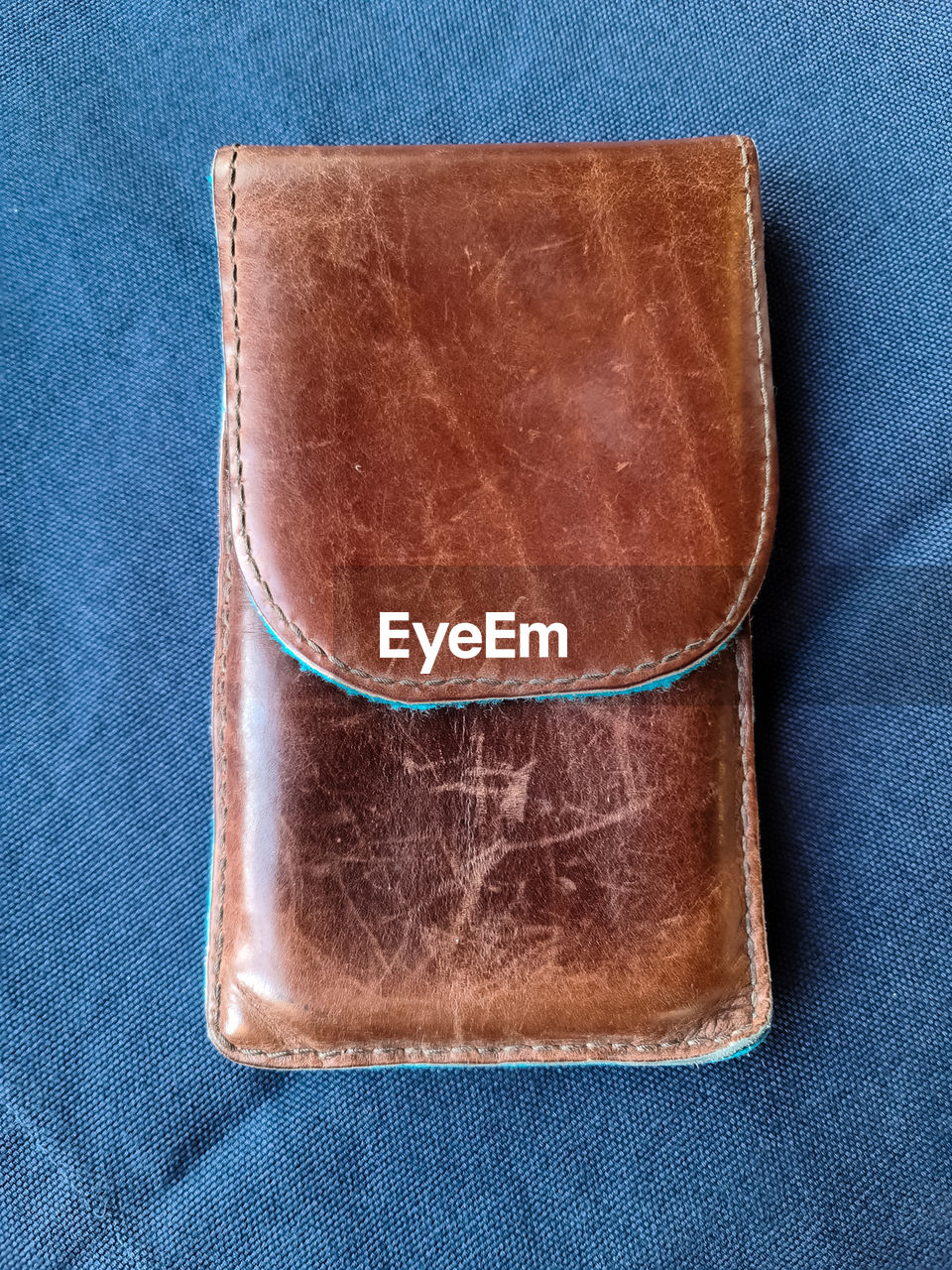 Brown handmade leather case for a smartphone on a blue background