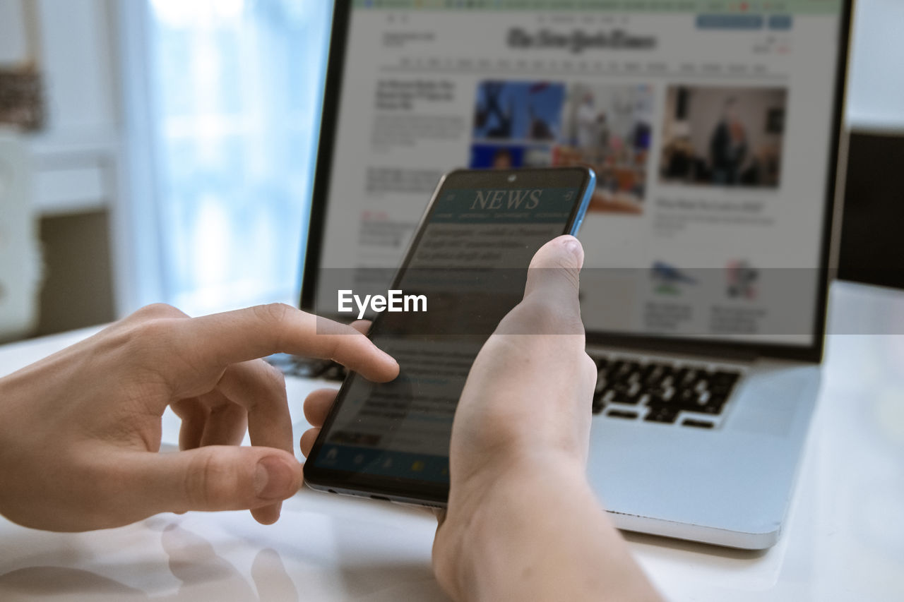 Man reading news online on a smartphone and laptop. reads articles, newspaper, information concept