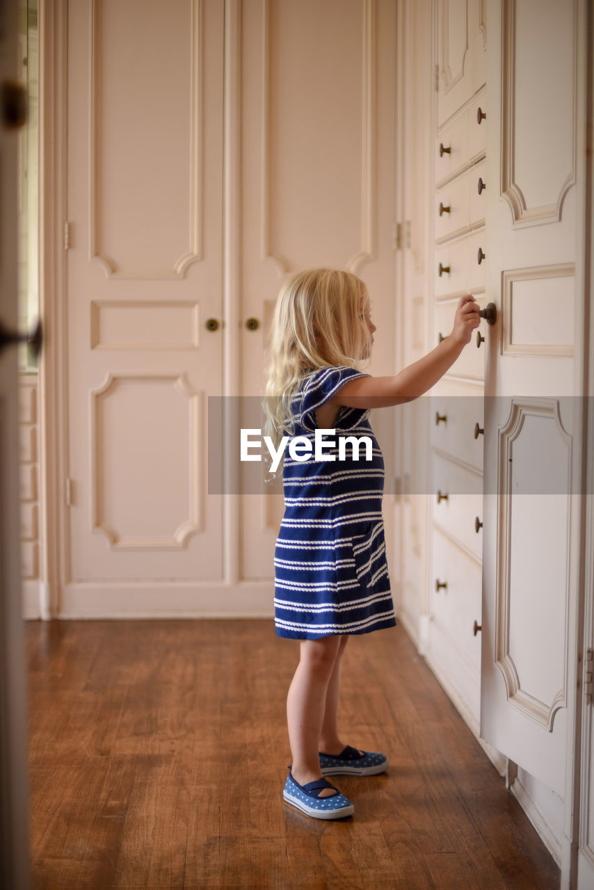 Full length of girl standing against door at home
