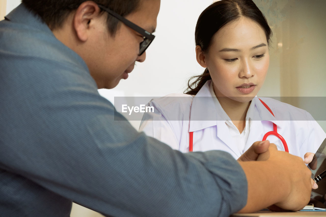 Female doctor with patient at desk in clinic