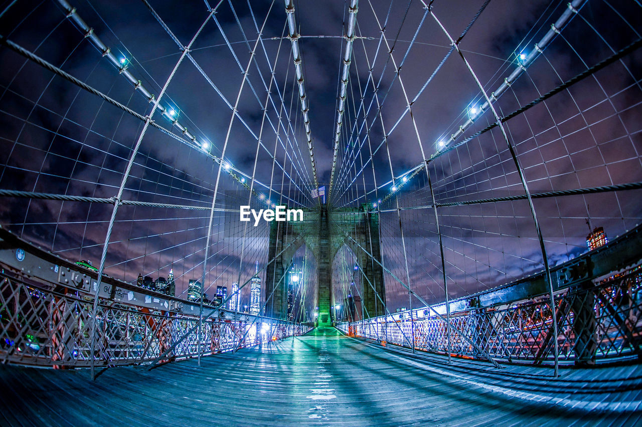 LOW ANGLE VIEW OF ILLUMINATED BRIDGE AT NIGHT