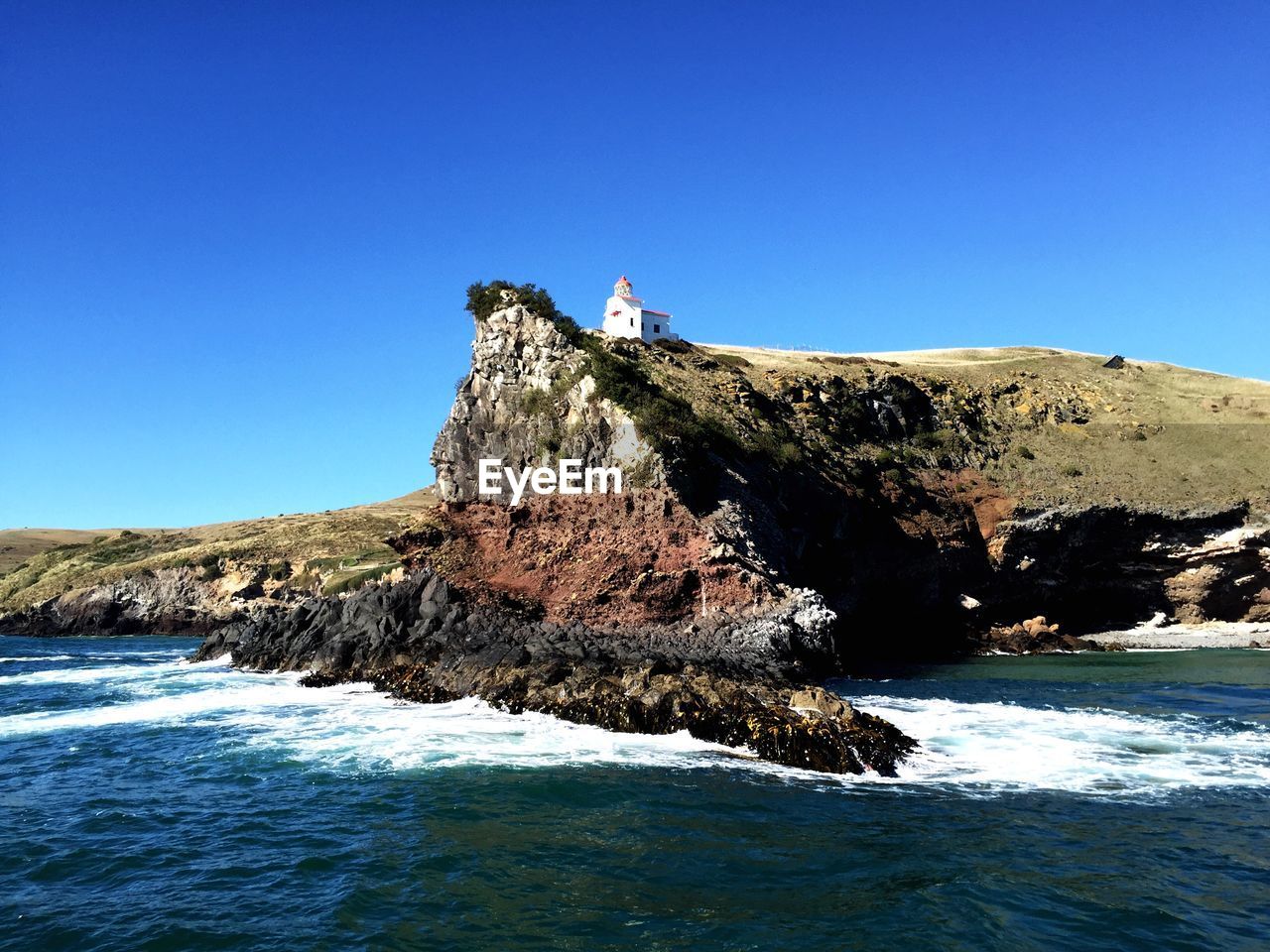 Lake in front of rock formation against clear blue sky