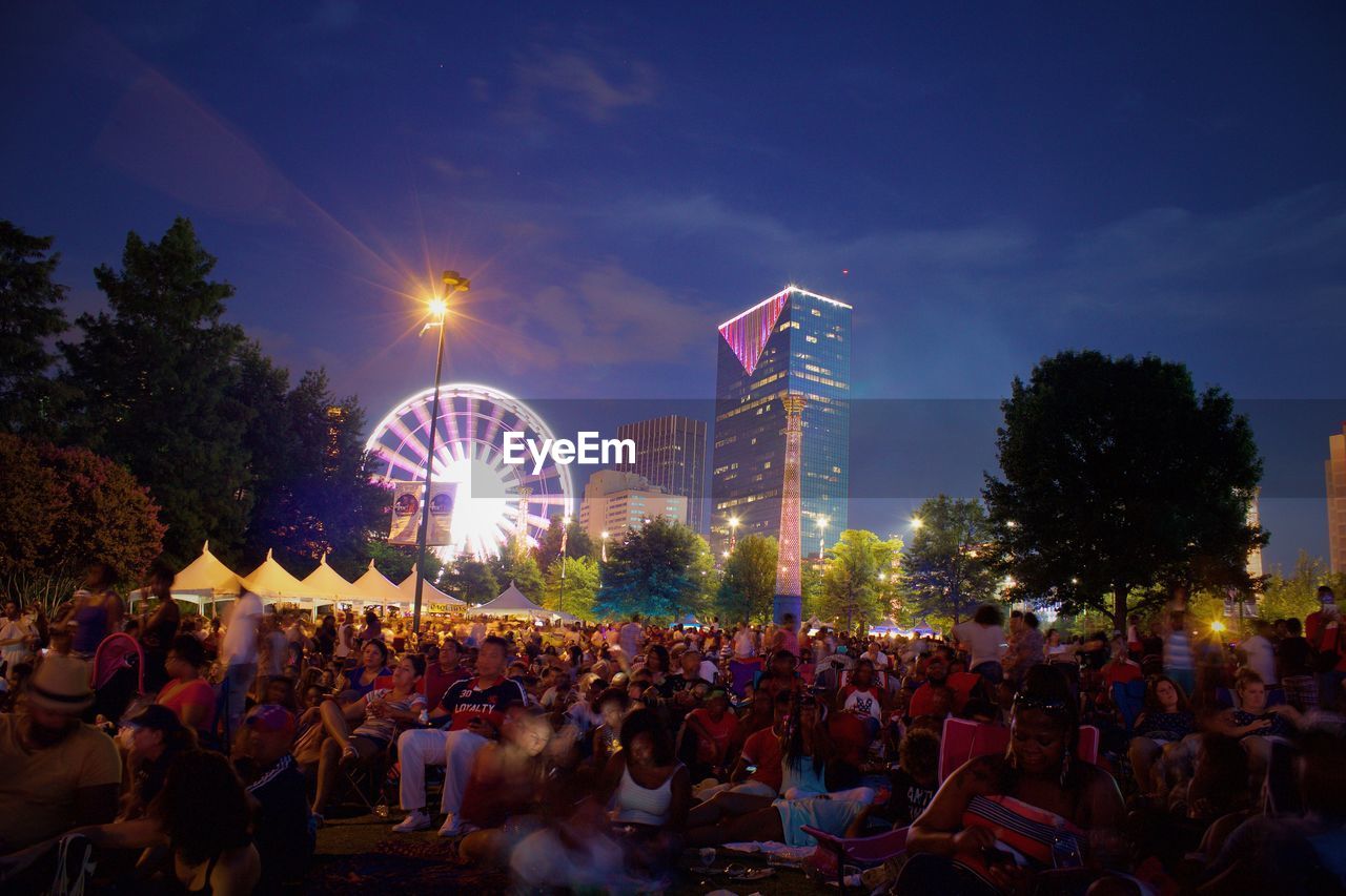 People at centennial olympic park against sky at night