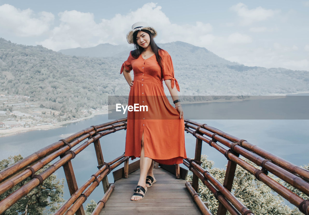 Portrait of woman standing on railing against mountain