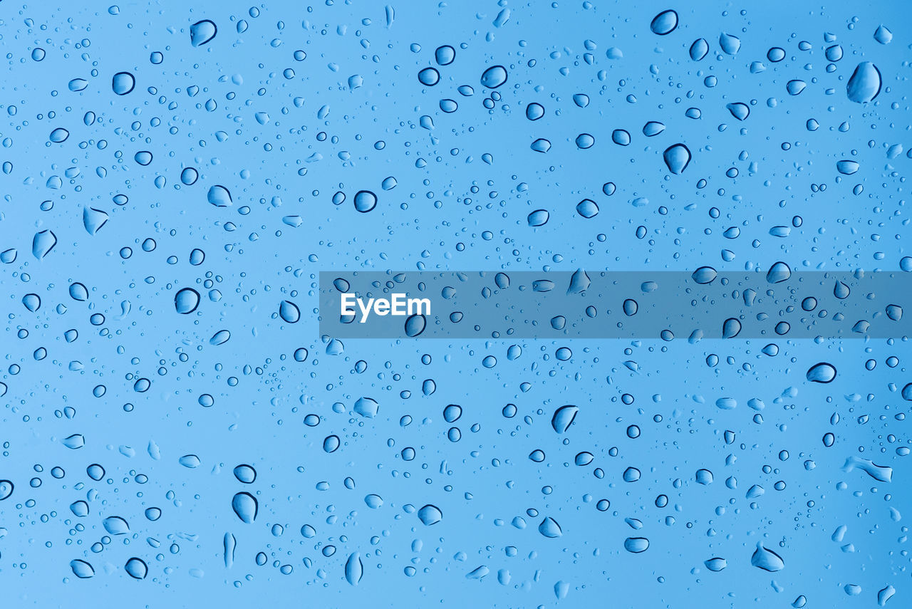 FULL FRAME SHOT OF RAINDROPS ON GLASS WINDOW