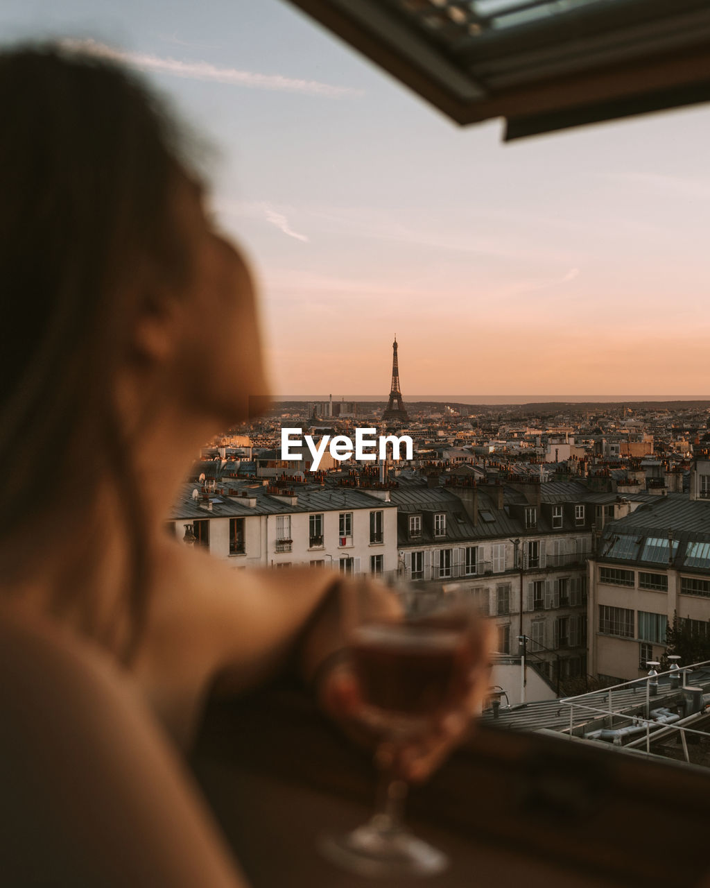 Close-up of woman holding wineglass looking at city