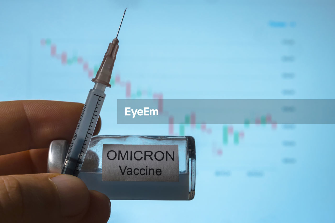 In his hand is a syringe and an ampoule with a vaccine against omicron, a new type of coronavirus