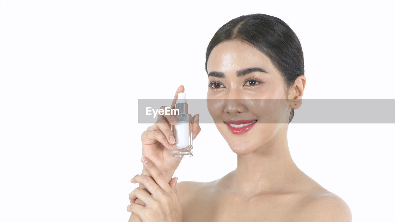 PORTRAIT OF A SMILING YOUNG WOMAN HOLDING WHITE BACKGROUND