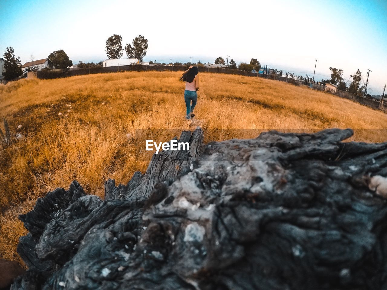 WOMAN WALKING ON FIELD AGAINST SKY