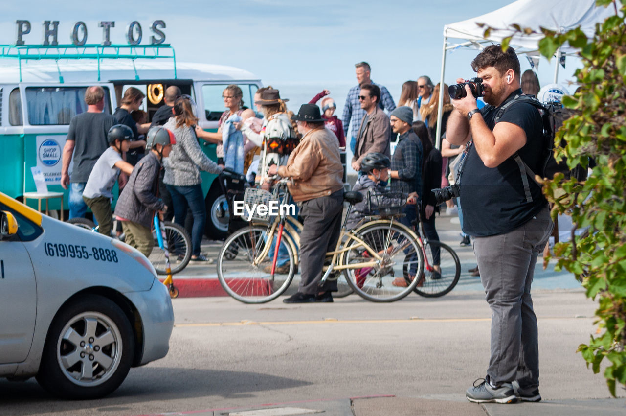 PEOPLE WITH BICYCLE STANDING IN FRONT OF A CITY