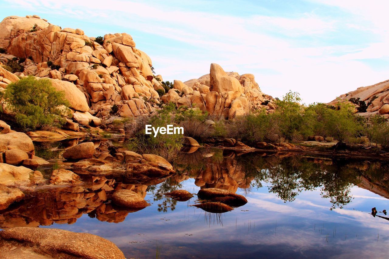 Rock formations reflecting on calm lake against sky