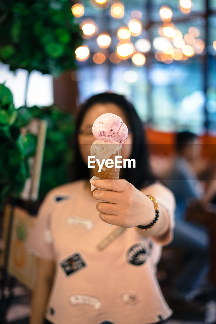 Woman holding ice cream cone in city at night