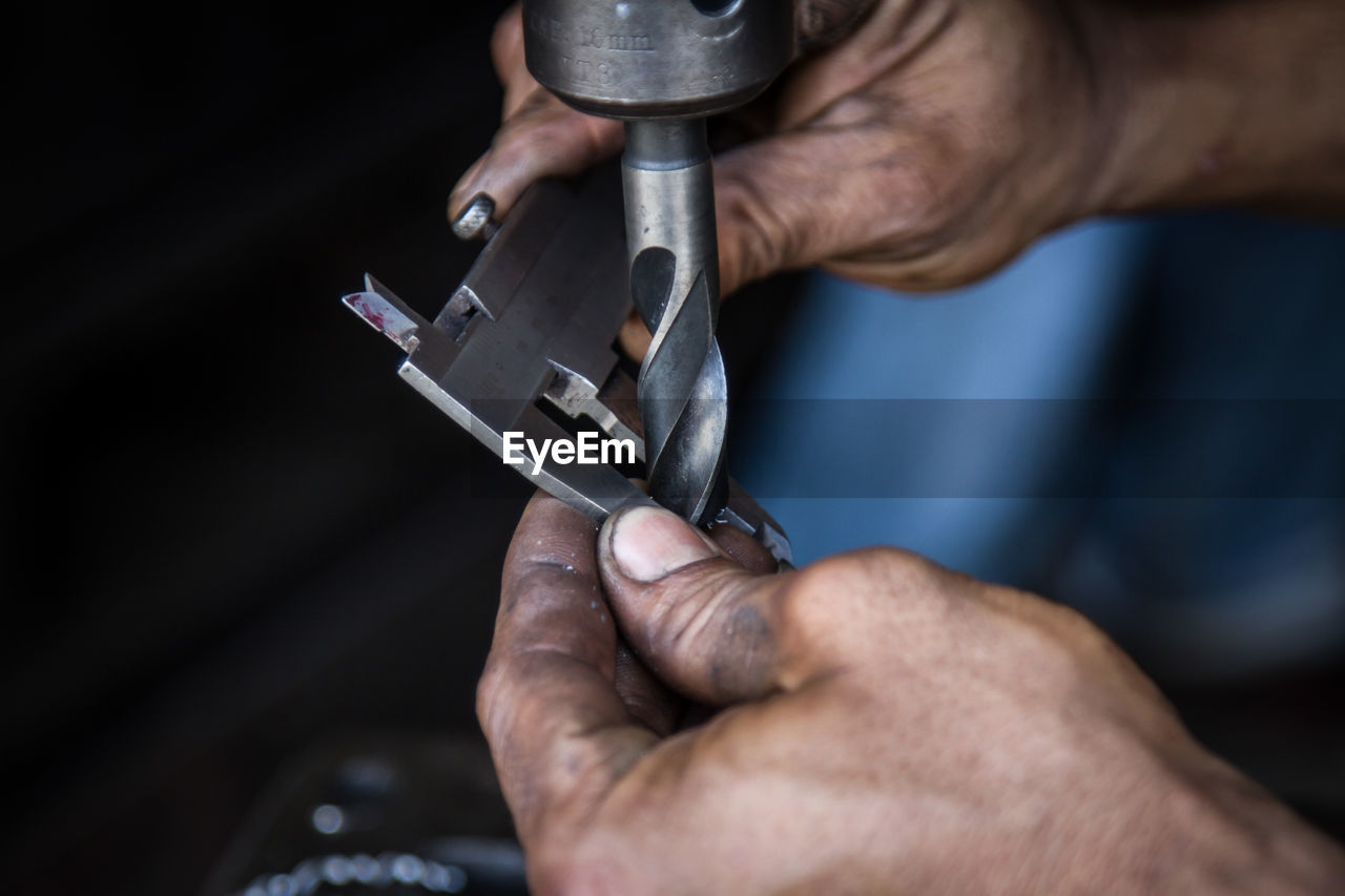 CLOSE-UP OF MAN WORKING ON METAL IN CONTAINER