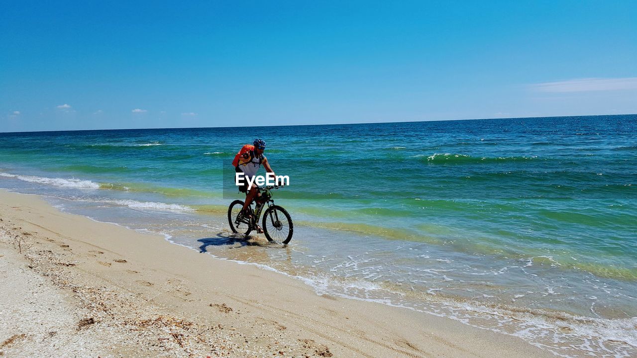 PERSON RIDING BICYCLE ON BEACH