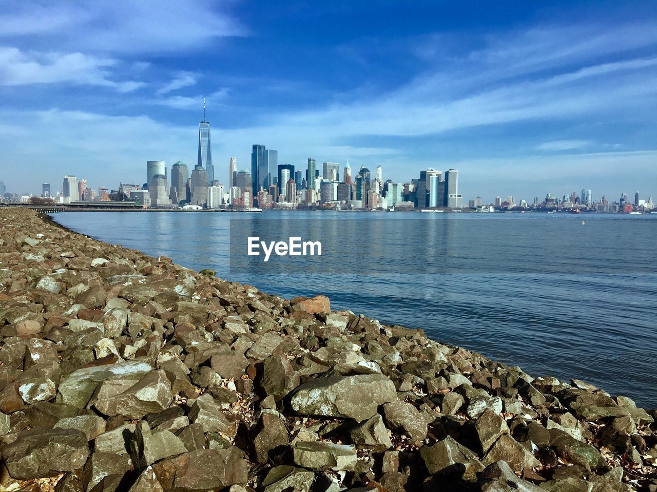 View of city at waterfront against cloudy sky