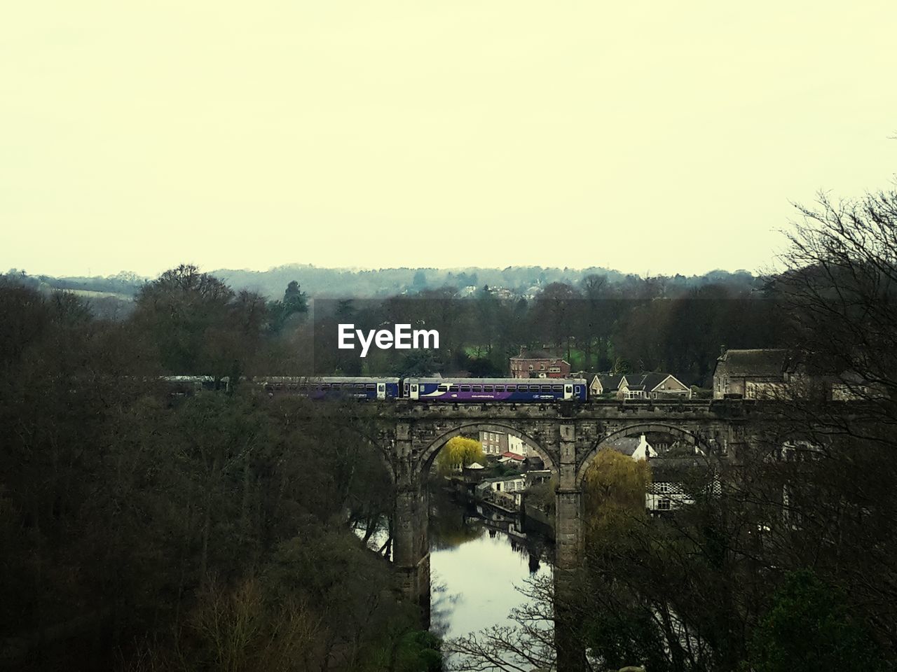 Train on railway bridge over river against sky