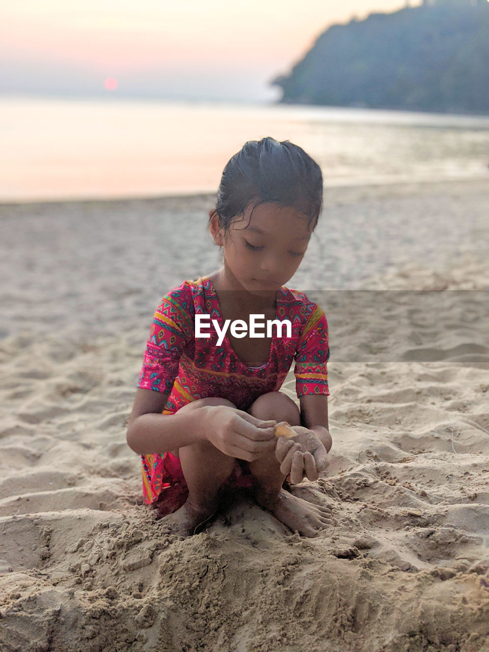 Full length of girl playing with sand on beach