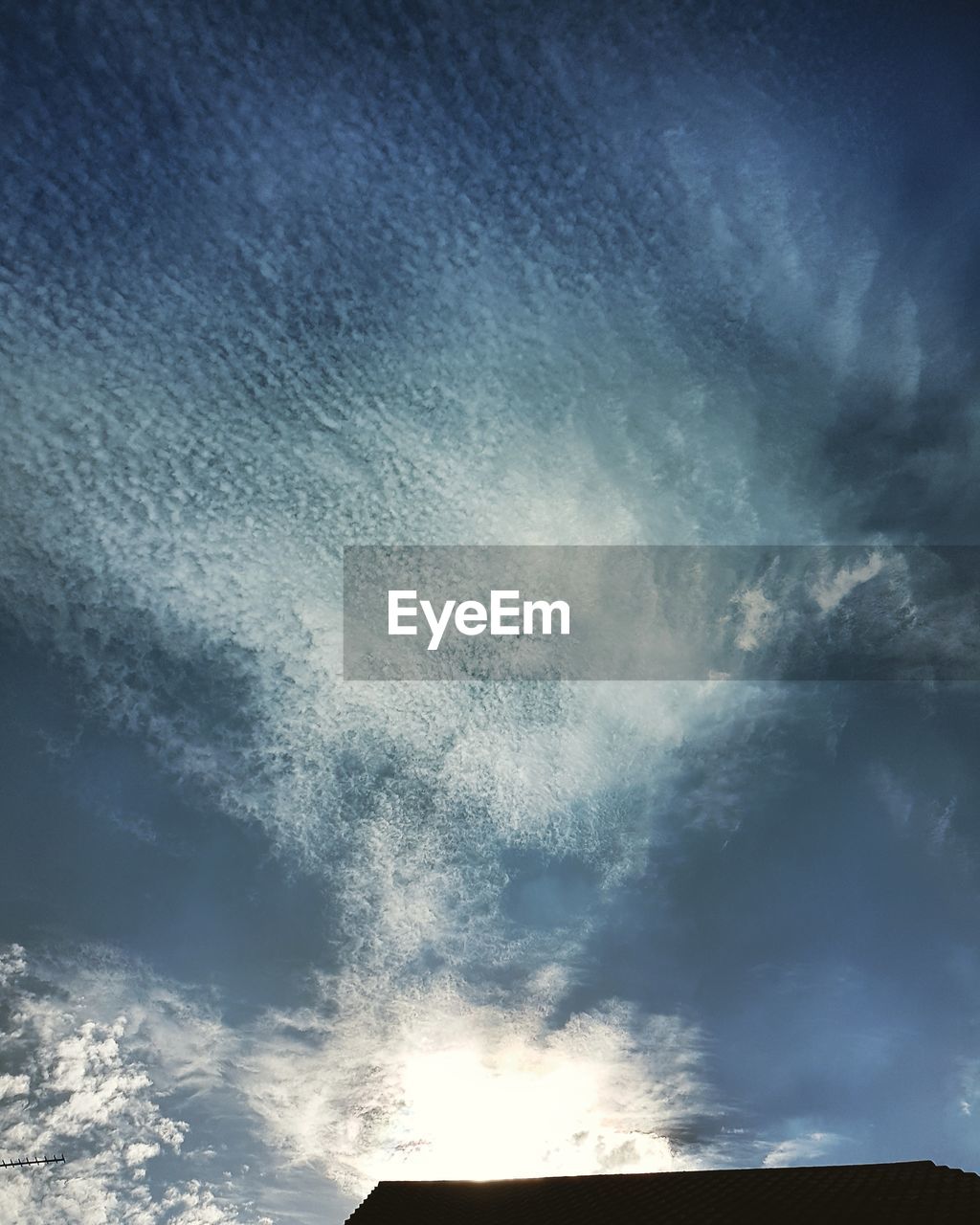 LOW ANGLE VIEW OF SUN STREAMING THROUGH CLOUDS