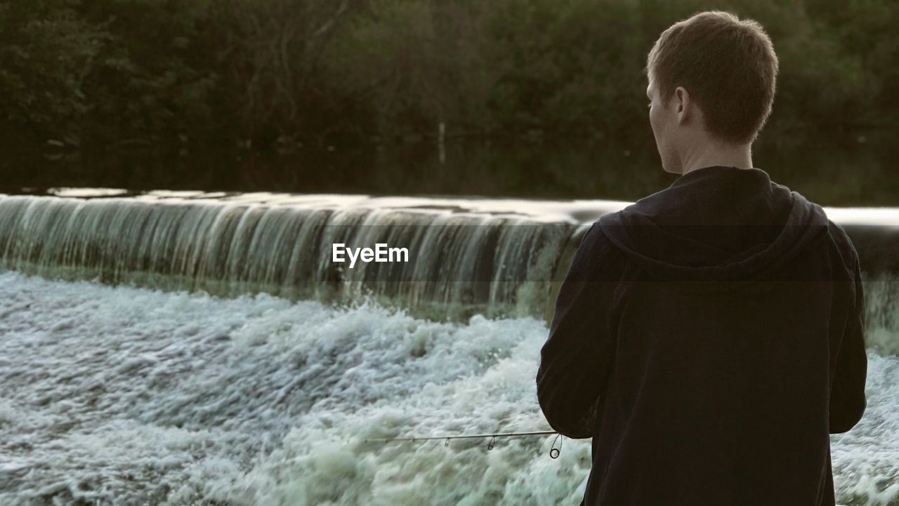 Rear view of man standing against dam