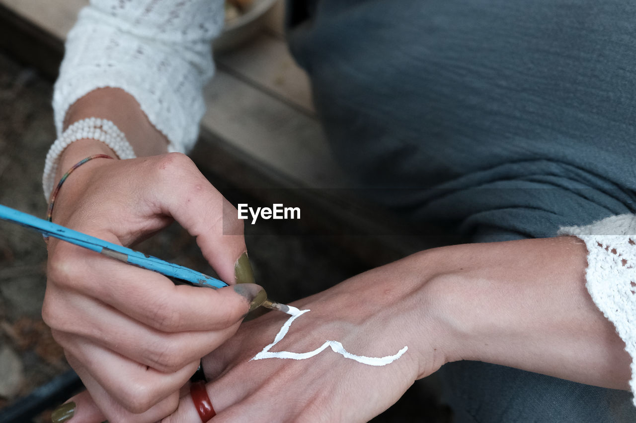 Low angle photo of woman painting her hand