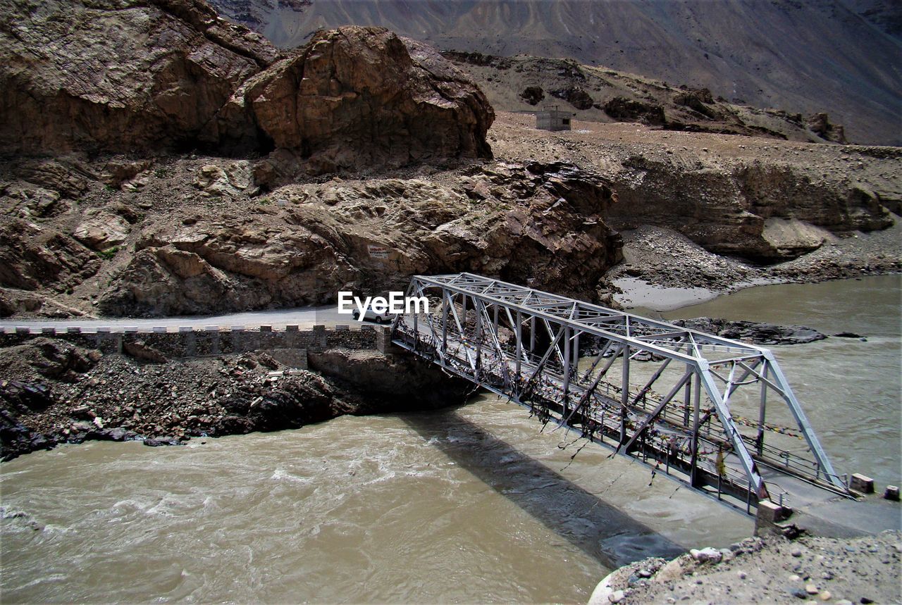 Rock formation by river against mountains