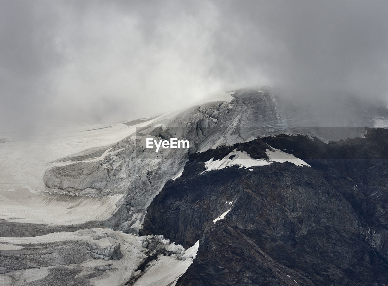 Scenic view of snowcapped mountains and icefall against cloudy  sky