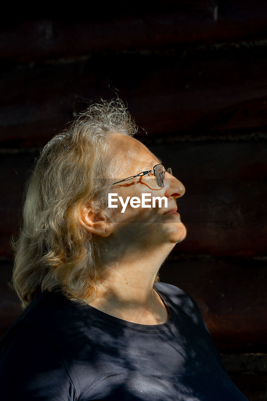 Portrait of elderly woman in glasses close-up on natural background. profile of man with sunset 