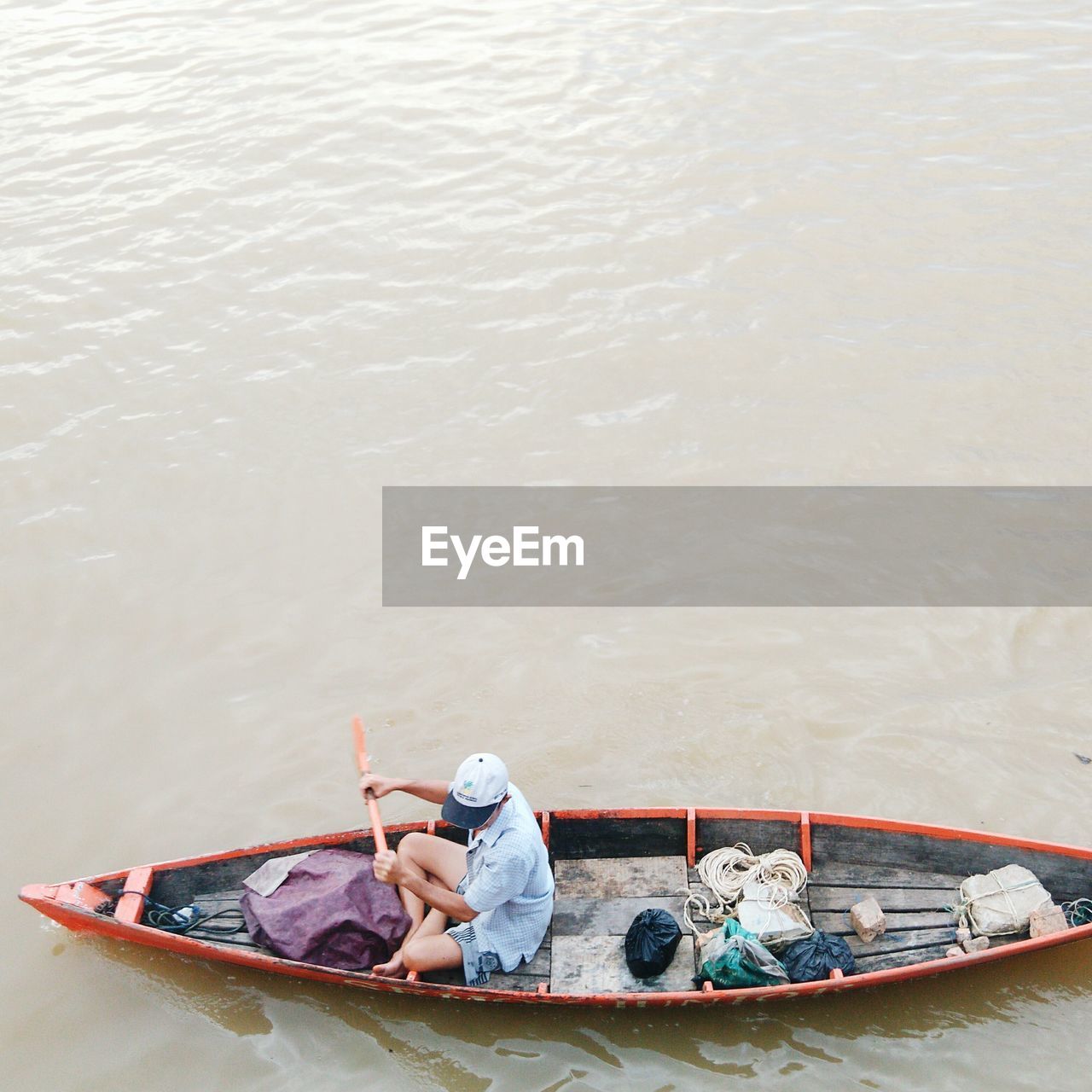 HIGH ANGLE VIEW OF BOY SITTING ON BOAT AT RIVER