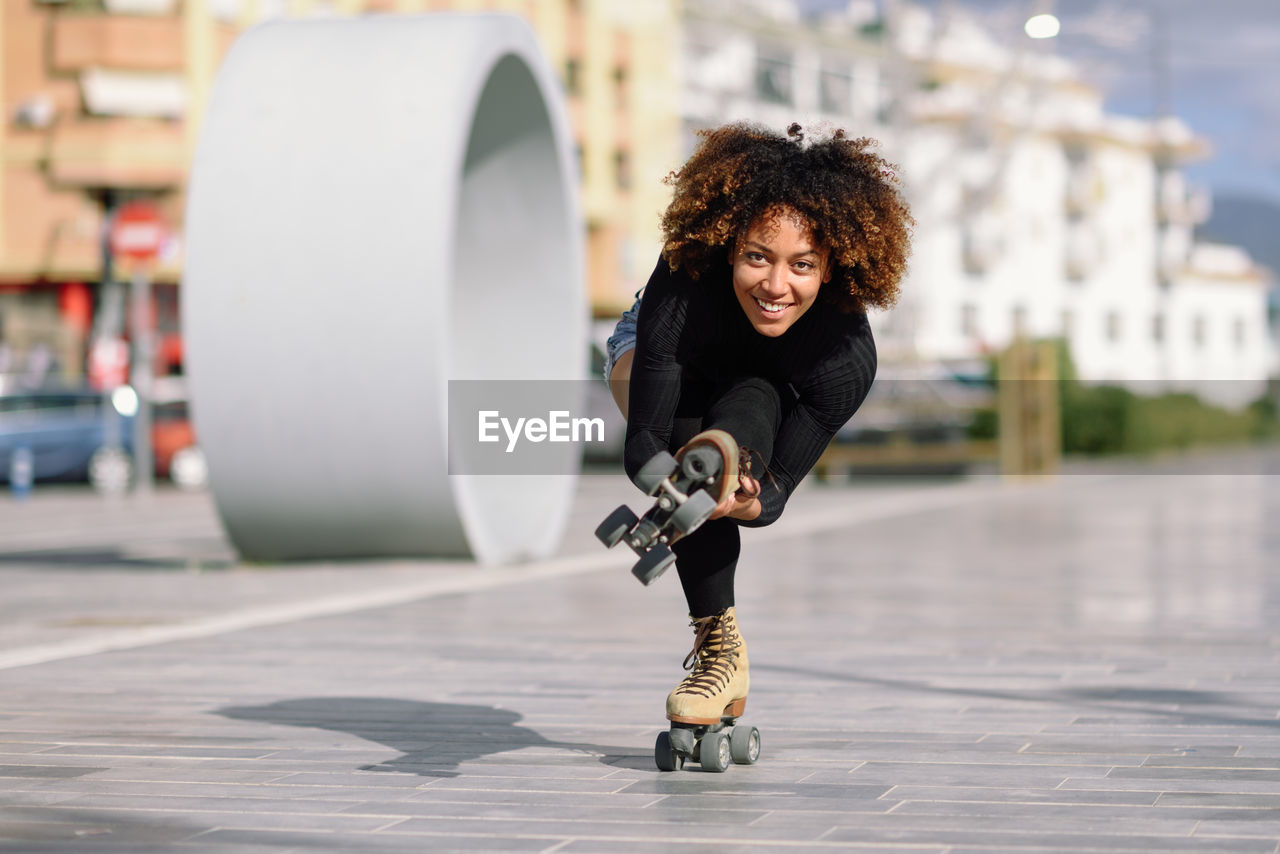 Full length of woman roller skating on footpath in city