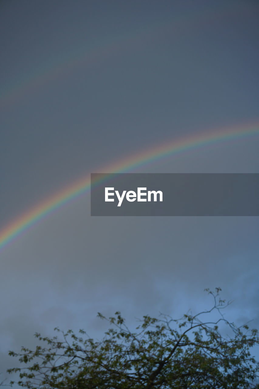 LOW ANGLE VIEW OF RAINBOW AGAINST CLOUDY SKY