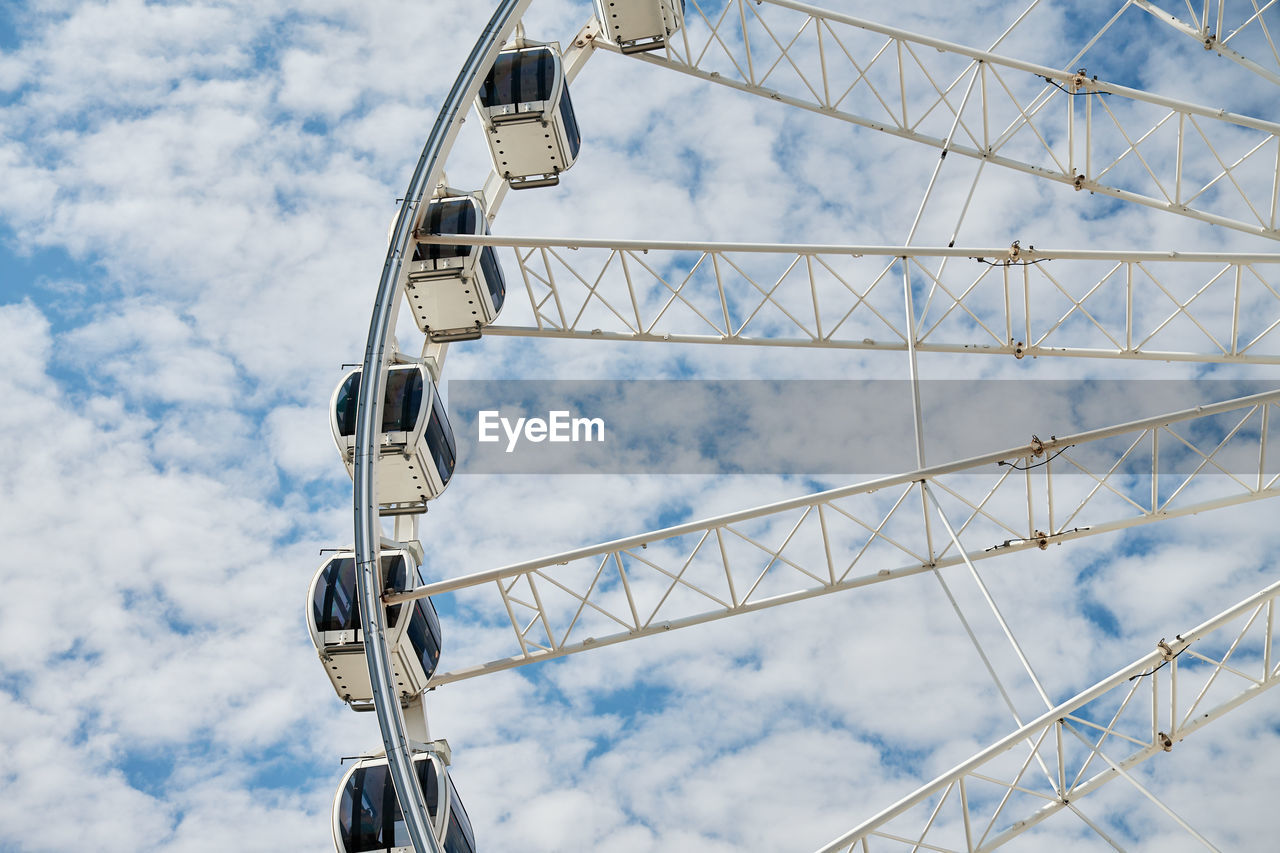 Ferris wheel rotates against background of blue cloudy sky. amusement park attraction