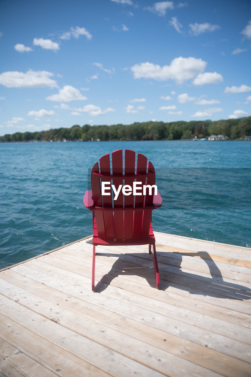 Red chair in swimming pool against sea