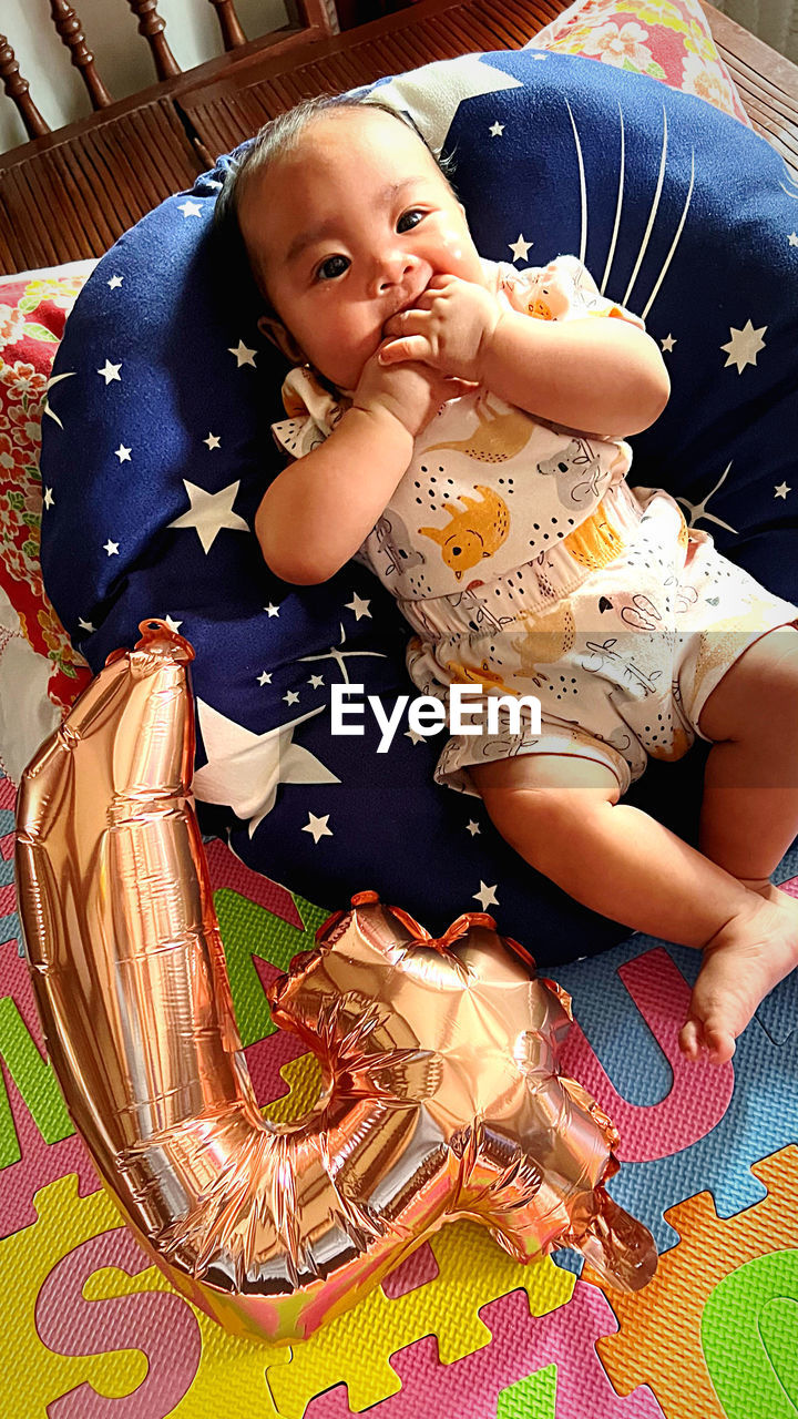 child, childhood, baby, one person, cute, innocence, indoors, full length, person, babyhood, lying down, toddler, portrait, high angle view, baby clothing, relaxation, looking at camera, lifestyles, emotion, clothing, sitting, furniture, female, women, home interior, bed, front view, happiness