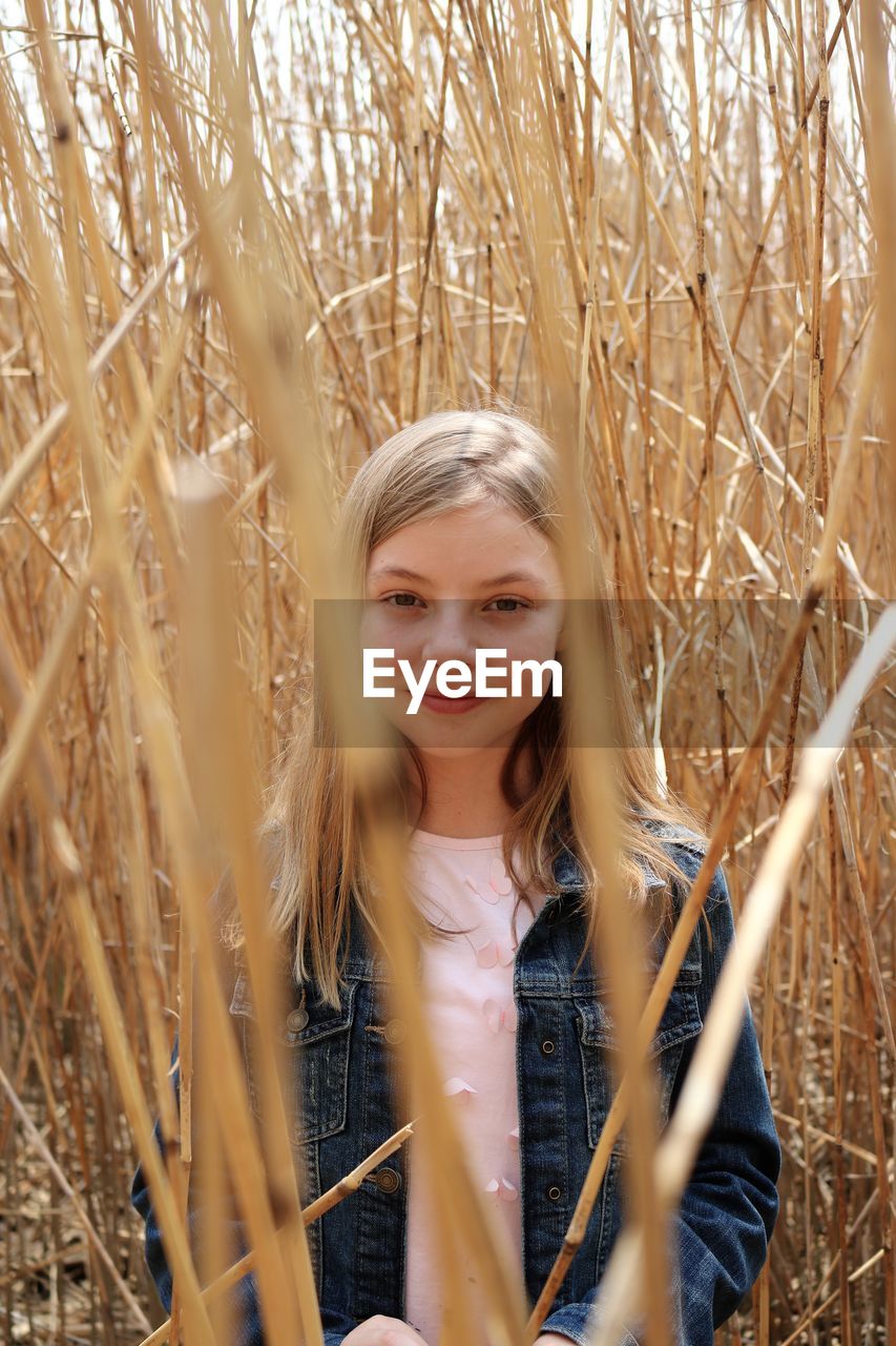 Portrait of smiling girl standing amidst dried plants