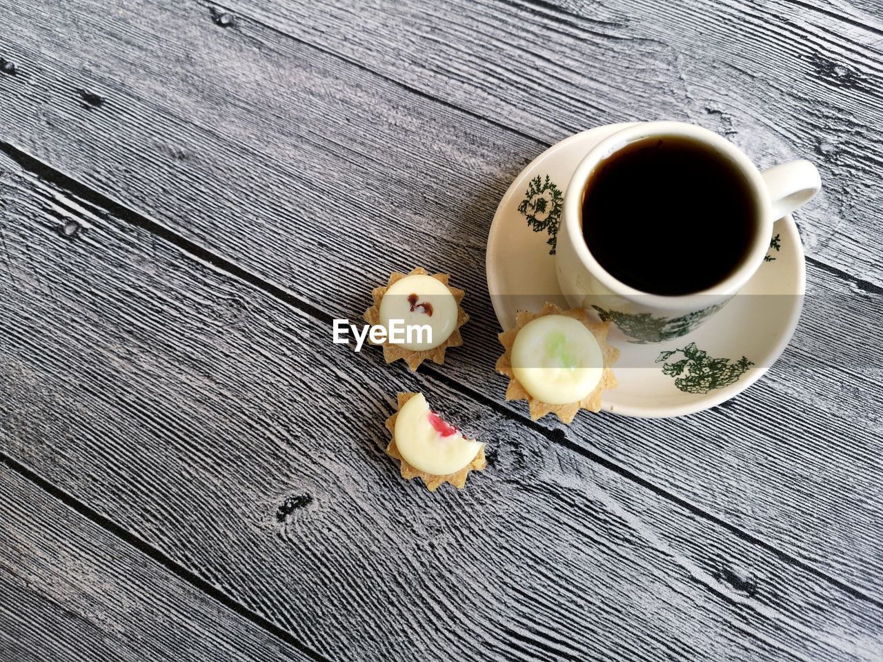 HIGH ANGLE VIEW OF COFFEE CUP ON WOODEN TABLE