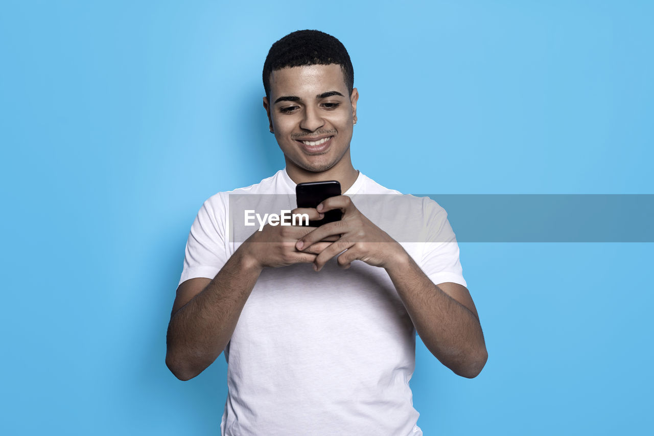 PORTRAIT OF YOUNG MAN HOLDING BLUE BACKGROUND