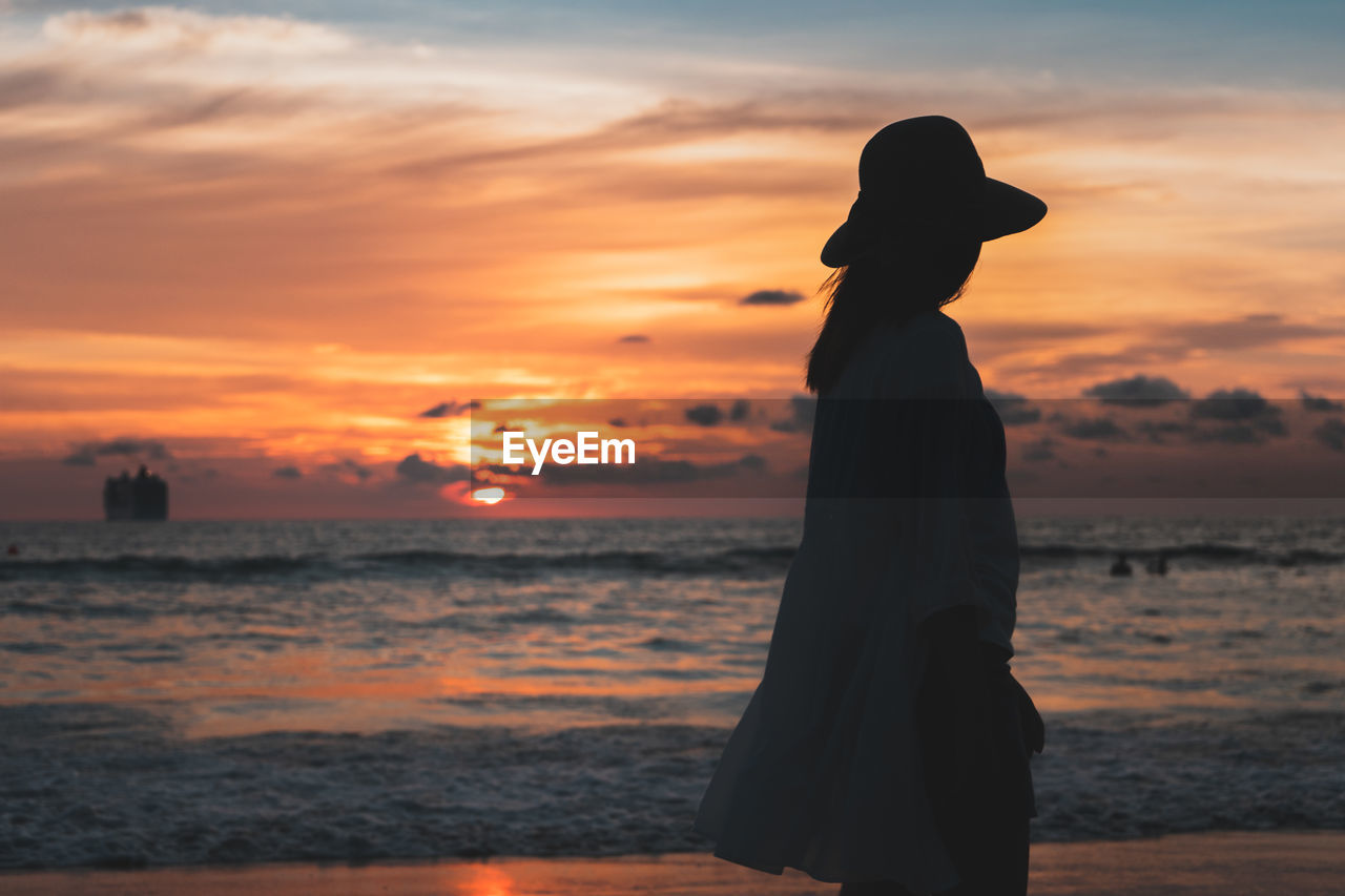 Silhouette woman looking at sea against sky during sunset