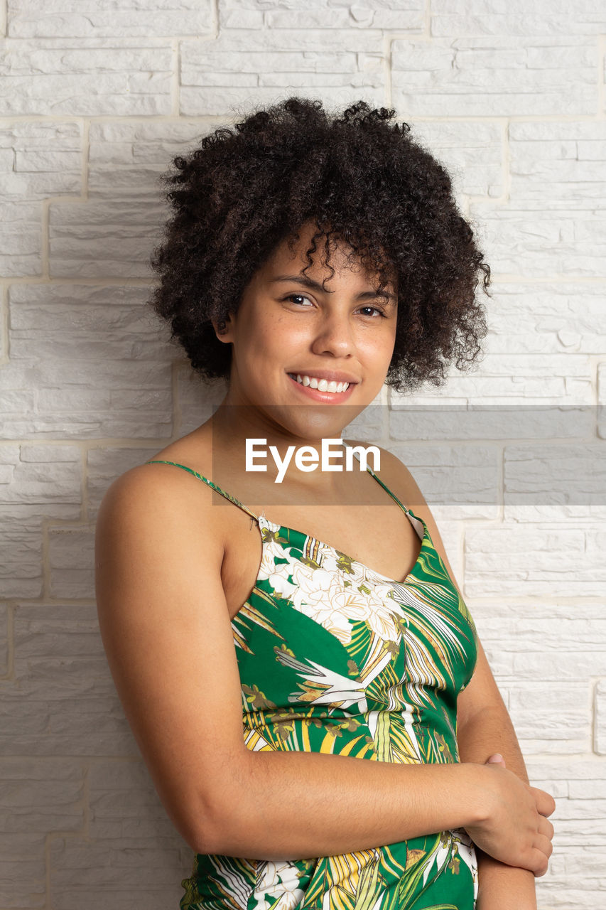 portrait of young woman standing against wall at home